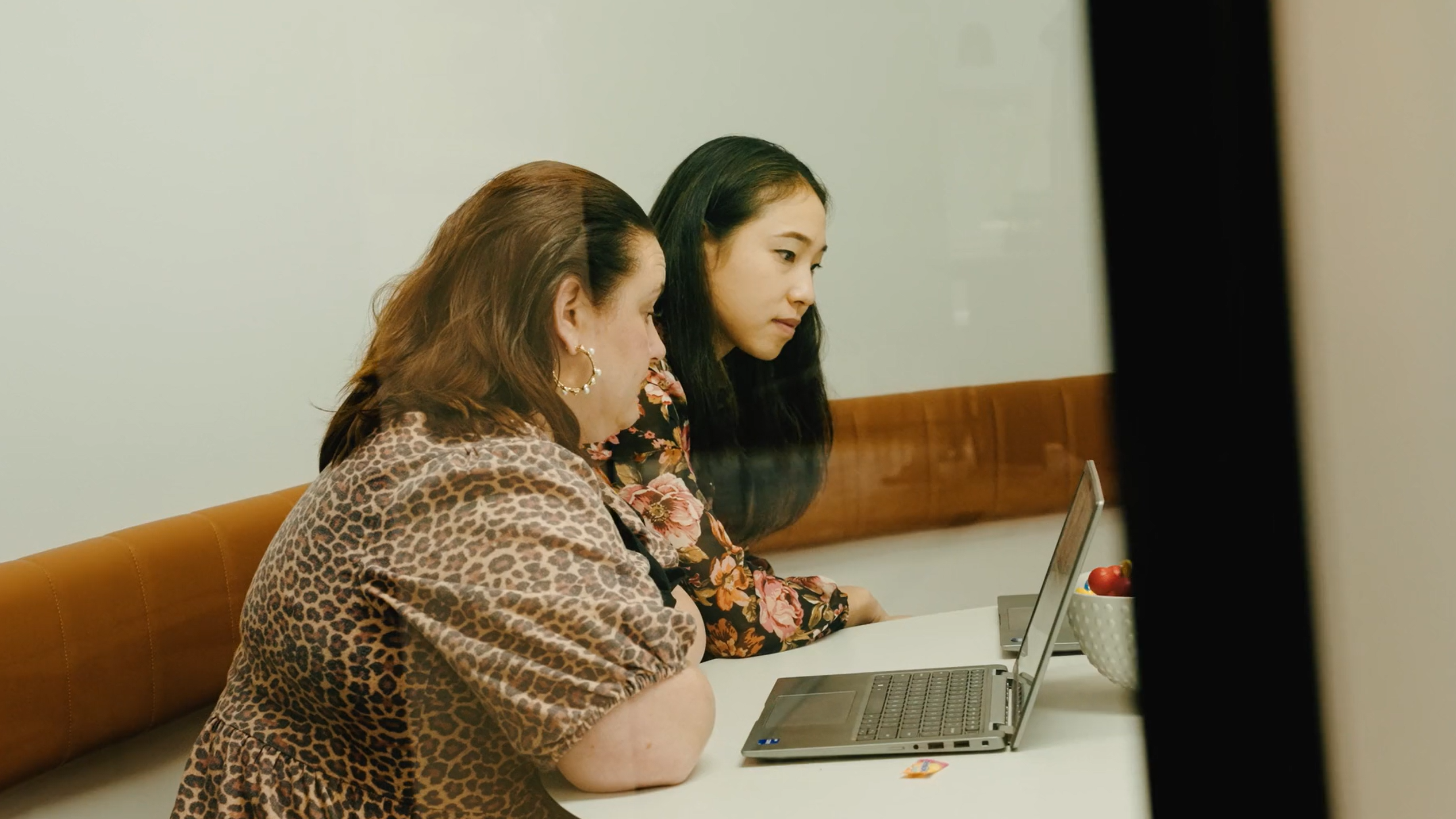 Two people sitting at a table looking at a laptop together